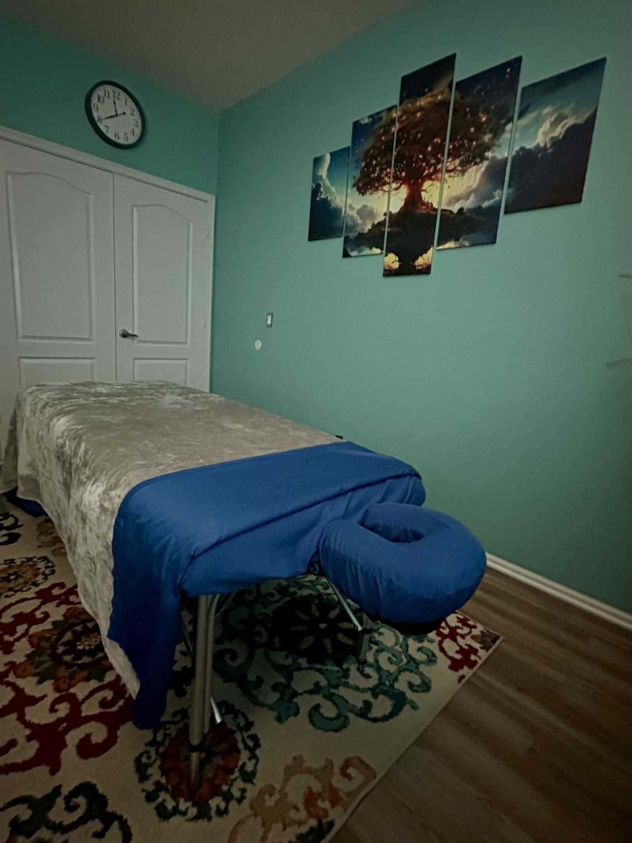 Massage table, blue linens, and artwork in the treatment room.