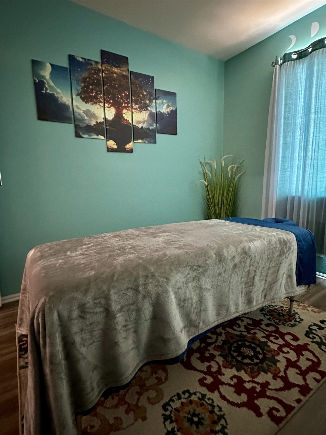 Tree wall art and teal wall in the massage studio.